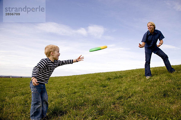 Junge und Vater spielen Frisbee