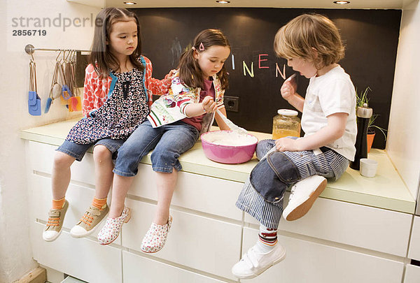 Zwei Mädchen und Jungen beim Kochen