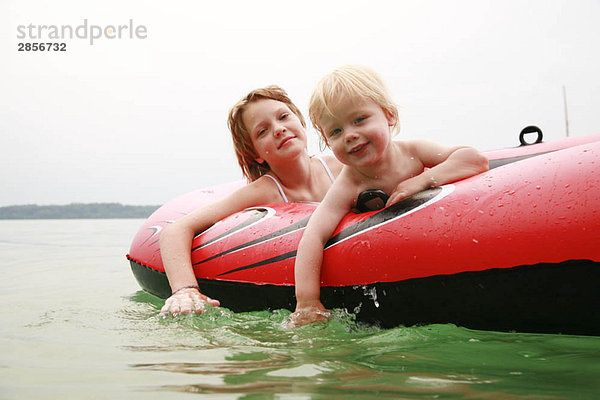 Mädchen und Junge schwimmen mit Gummiboot