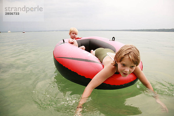 Mädchen und Junge schwimmen mit Gummiboot