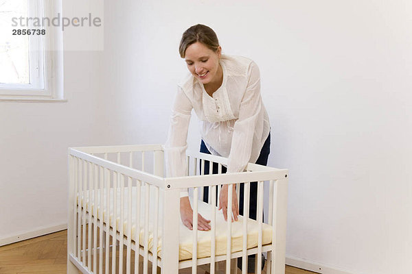 Schwangere Frau beim Zusammenstellen des Babybettes