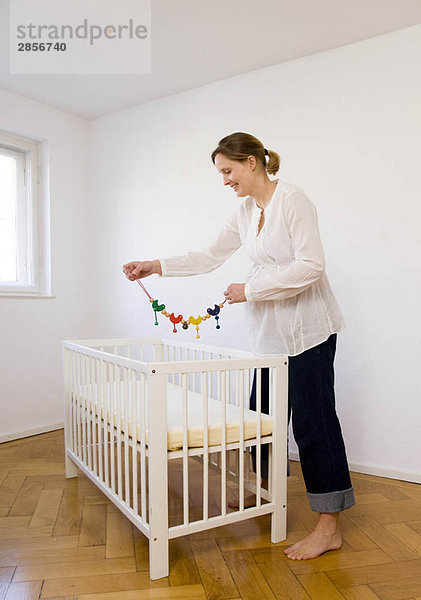 Eine schwangere Frau  die sich ein mobiles Spielzeug ansieht.