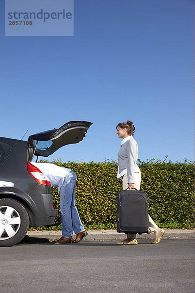 Pärchen  das Taschen ins Auto steckt