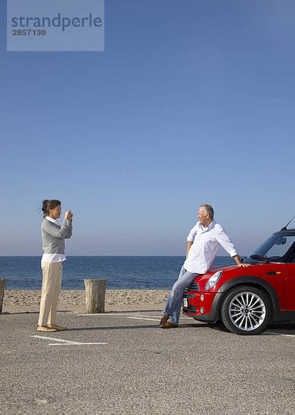 Frau fotografiert Mann mit dem Auto