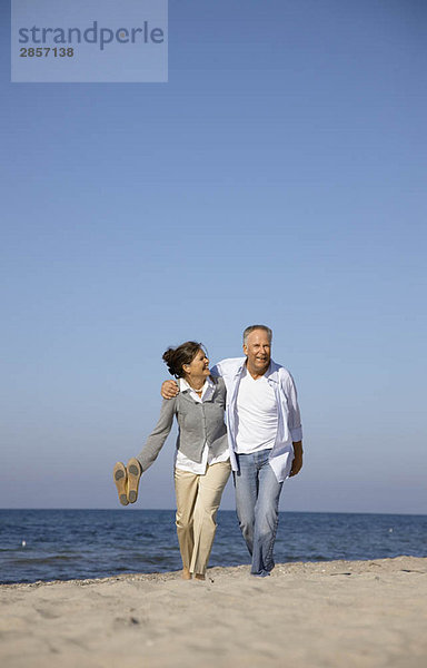 Erwachsene Paare  die am Strand spazieren gehen