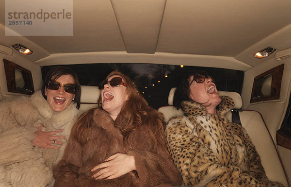 Drei Frauen auf dem Rücksitz eines Luxusautos