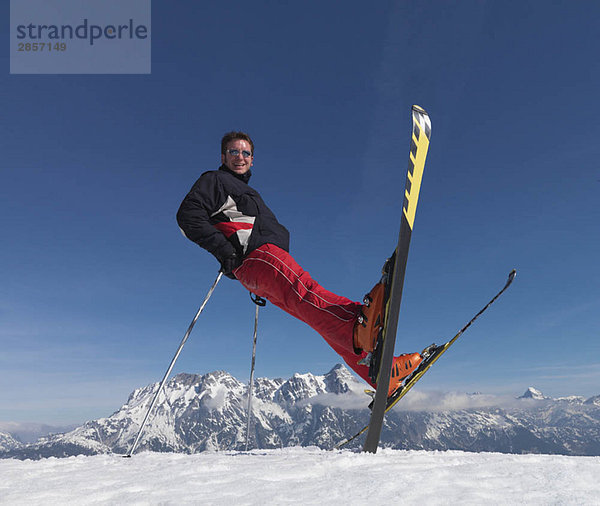Mann balanciert auf Skiern und Skistöcken