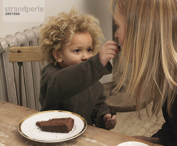 Kleiner Junge füttert Mutter mit Kuchen