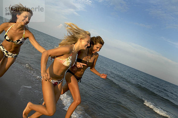 Teenager-Mädchen  die am Strand rennen.