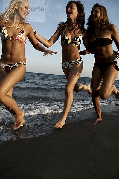 Teenager-Mädchen  die am Strand rennen.