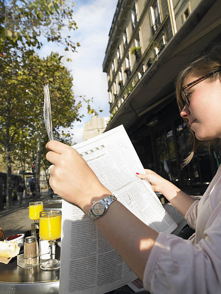 Frau liest Zeitung im Café
