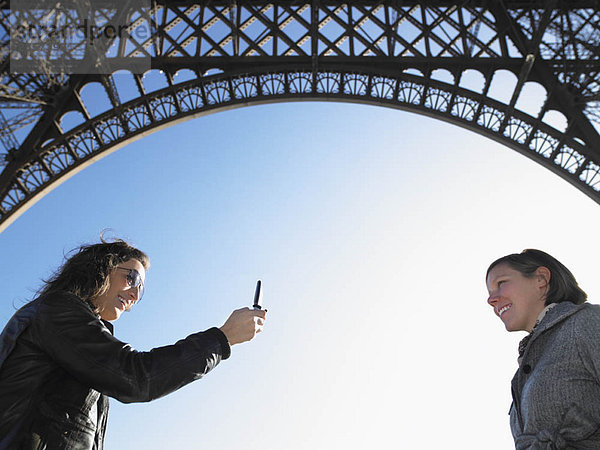 Frauen fotografieren unter dem Eiffelturm