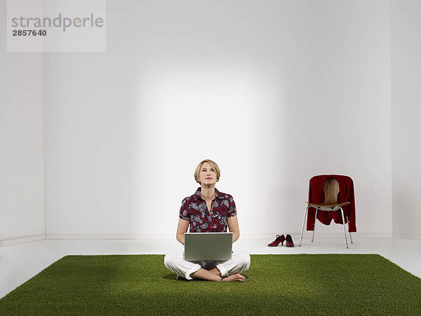 Frau auf Rasen sitzend mit Laptop