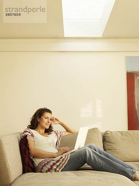 Frau auf dem Sofa sitzend mit Laptop