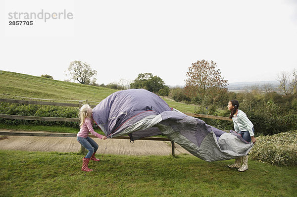 Zwei Mädchen bauen ein Zelt auf