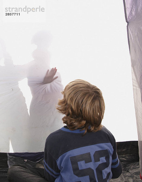 Junge schaut auf Schatten im Zelt