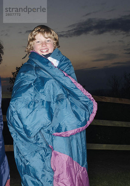 Junge im Schlafsack in der Abenddämmerung