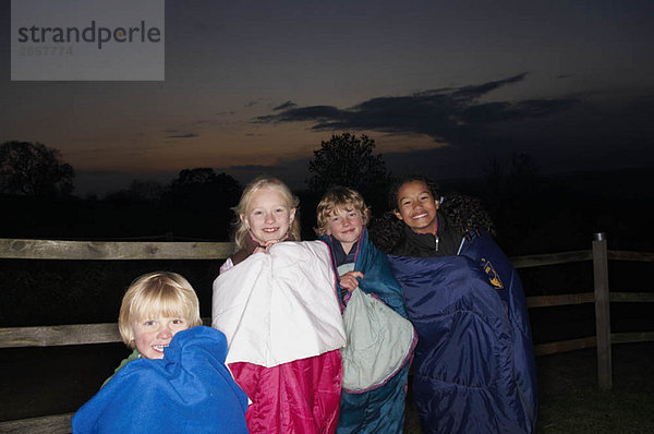 Kinder in Schlafsäcken in der Abenddämmerung