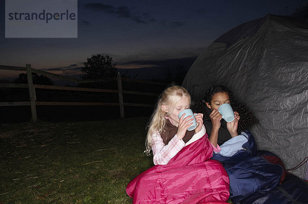Mädchen trinken heißes Getränk in der Nähe des Zeltes