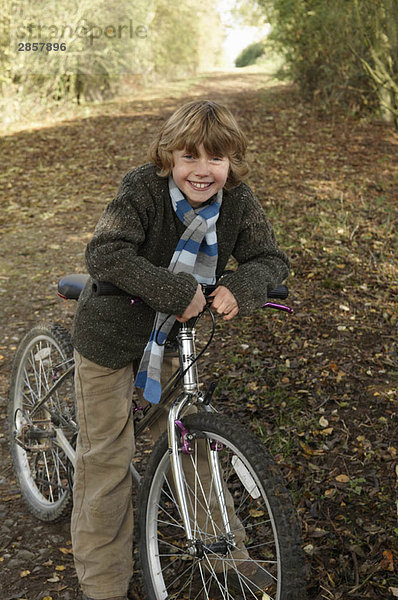 Junge mit Fahrrad auf dem Landweg