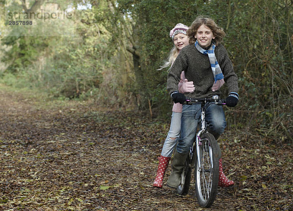 Junge und Mädchen teilen sich das Fahrrad in der Natur