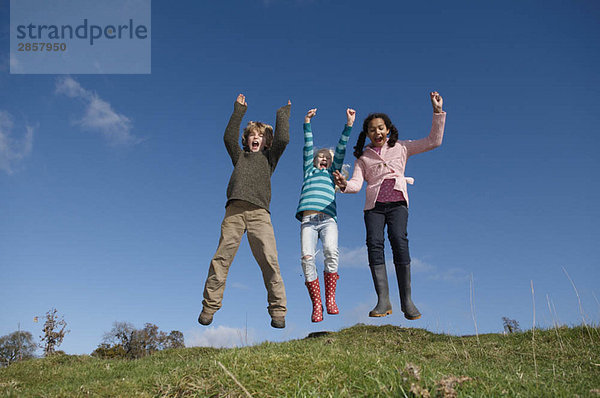 Drei Kinder springen auf dem Hügel