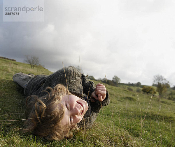 Junge auf Gras am Hang liegend