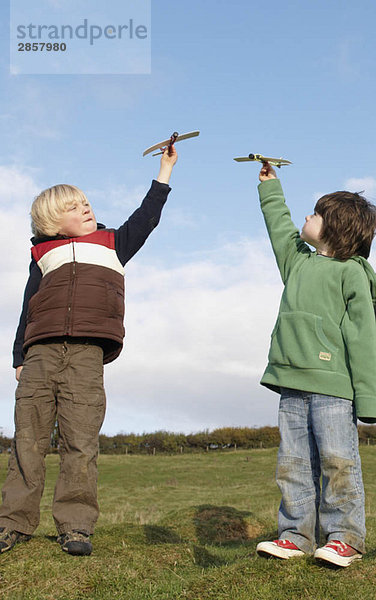 Jungen mit Spielzeugflugzeugen im Feld