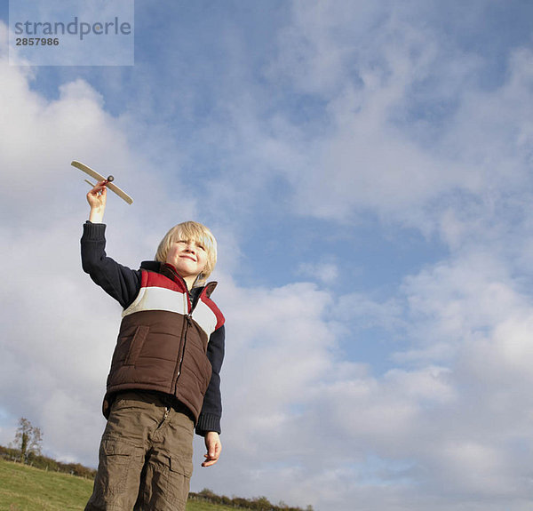 Kleiner Junge mit Spielzeugflugzeug auf dem Lande