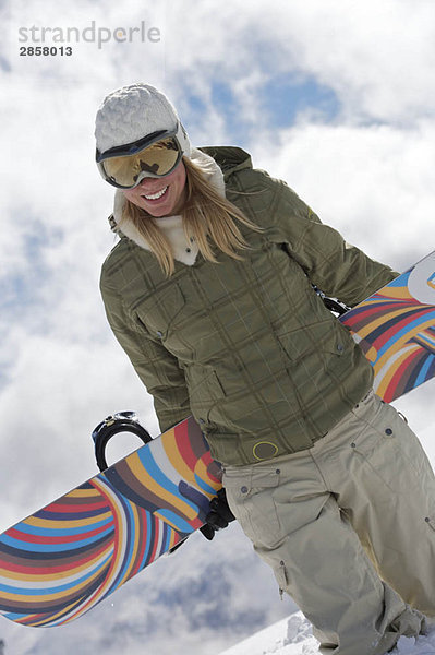 Weibliche Snowboarderin  die mit ihrem Schnee spazieren geht.