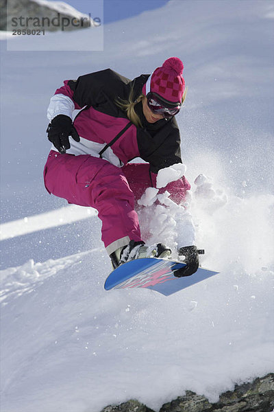 Snowboarderin beim Springen mit Greifer