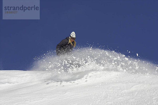 Weibliche Snowboarderin beim Drehen im Schnee