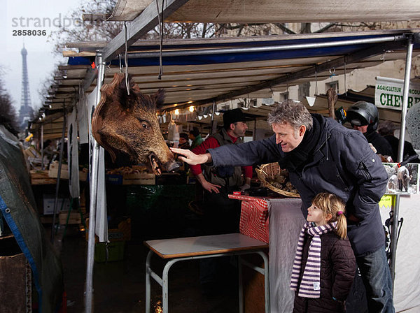 Vater berührt Eberkopf auf dem Markt