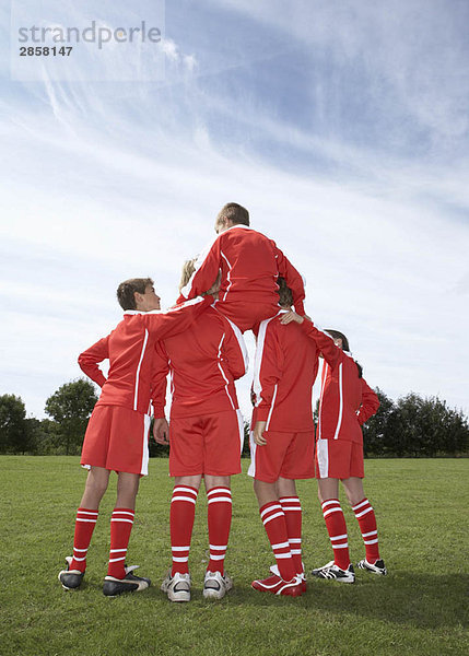 Fußballspieler sitzt auf den Schultern eines Teams