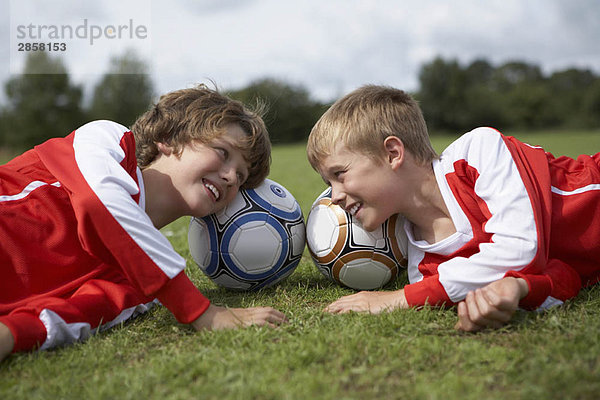 Zwei Jungen  die mit Köpfen auf Bällen lachen.