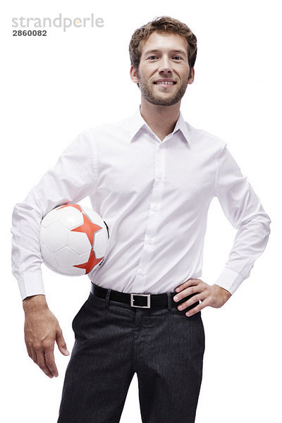 Junger Mann hält Fußball  lächelnd  Porträt