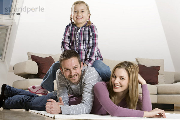 Parents and daughter (3-4)  relaxing at home