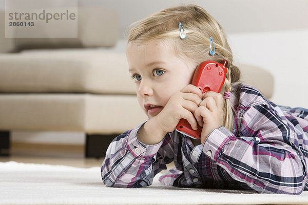 Kleines Mädchen (3-4) mit Spielzeugtelefon