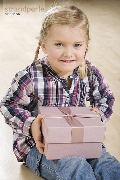Kleines Mädchen (3-4) mit Geschenkpaket  lächelnd