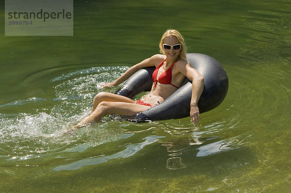 Österreich  Salzburger Land  Reitecksee  Junge Frau entspannt auf Schwimmreifen