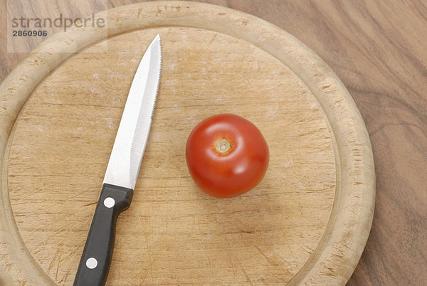 Tomate und Messer auf Schneidbrett  erhöhte Ansicht