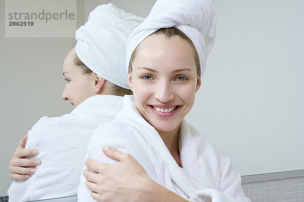Junge Frau im Bademantel und Handtuch über dem Kopf  lächelnd  Portrait