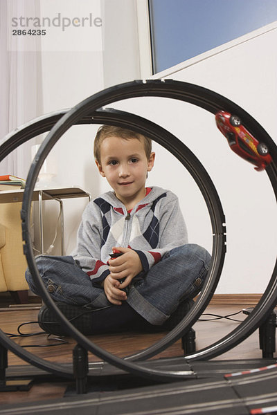 Junge (4-5) spielt mit Spielzeugrennbahn