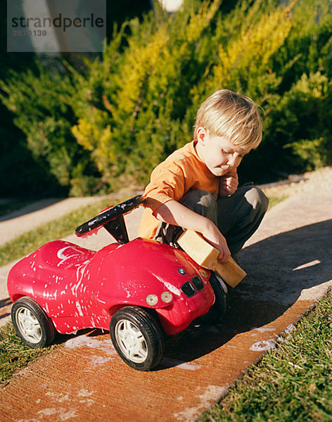 Ein Junge eine rote Auto waschen.