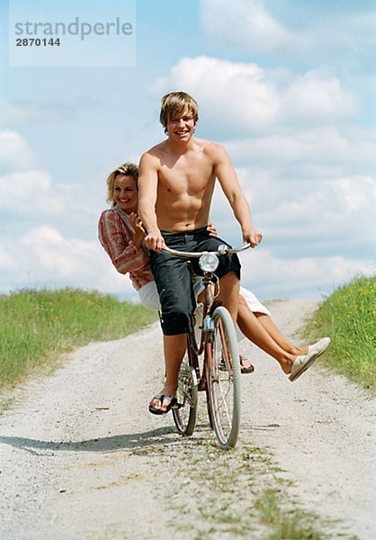 Ein junger Mann und eine junge Frau auf dem Fahrrad am sonnigen Tag Schweden.