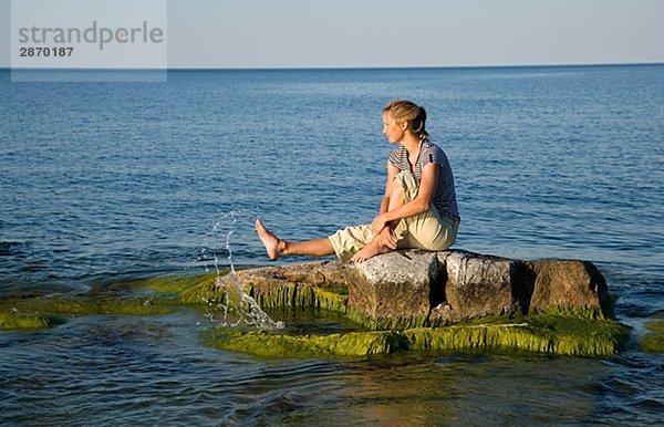 Eine Frau sitzend auf einem versunkene Felsen Östergötlands Schweden.