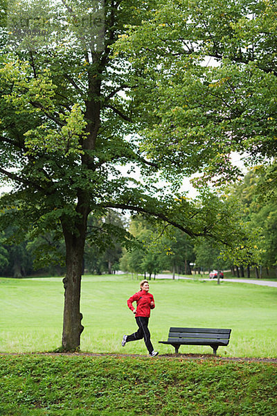 Eine Frau in einem Park Schweden Joggen.