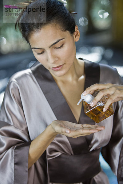 Frau gießt Öl aus einem Spender auf die Hand