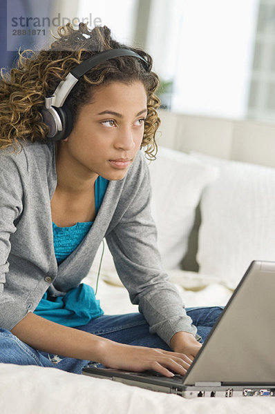 Mädchen arbeitet an einem Laptop und hört sich Kopfhörer an