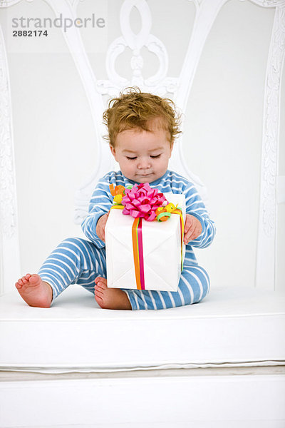Kleiner Junge mit einem Geschenk im Sessel
